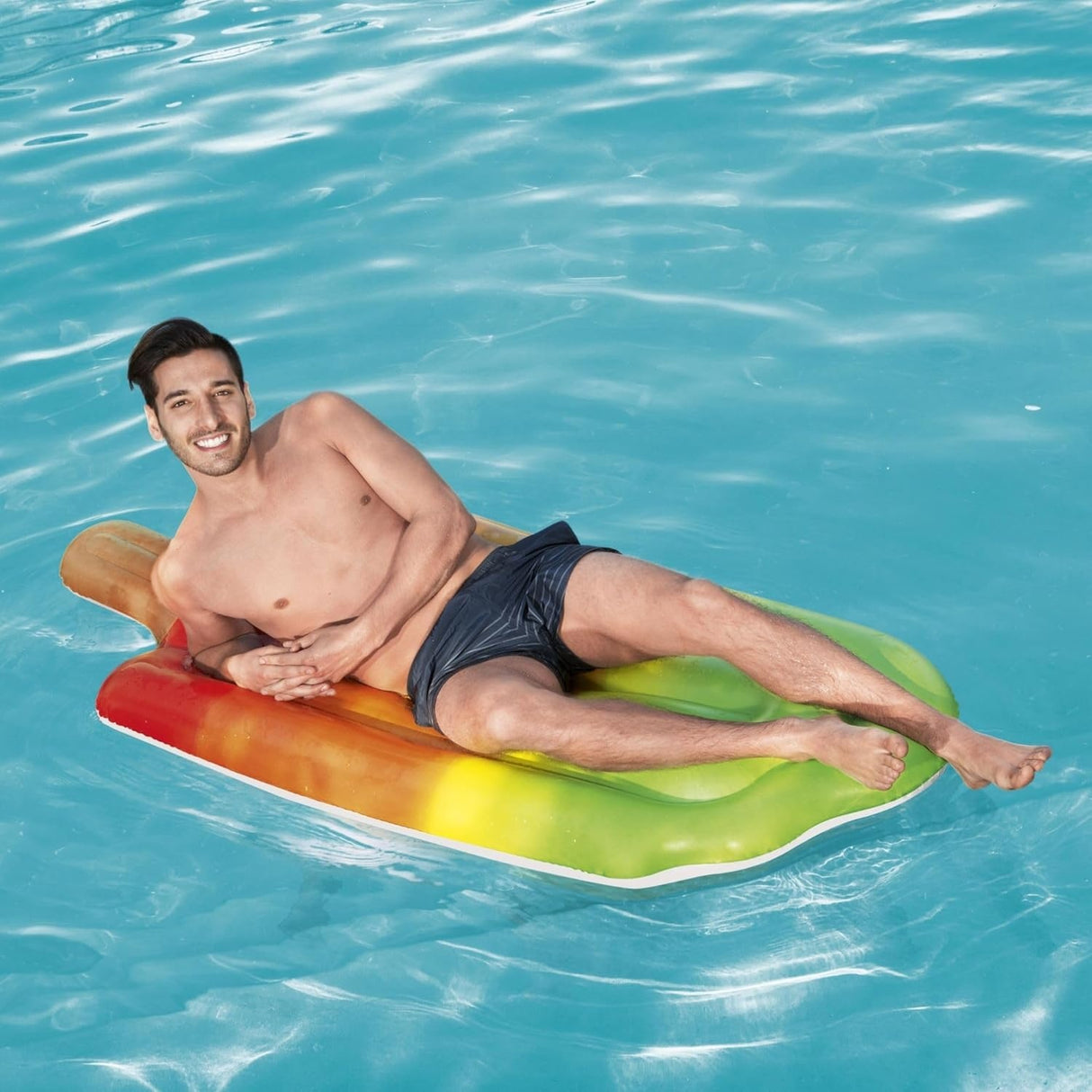 This is a lifestyle image showing a man resting on the pool float in the pool.