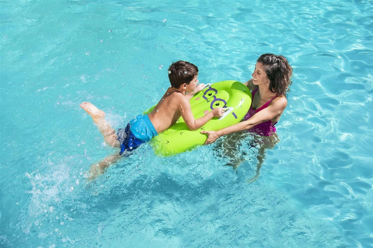 This is a lifestyle image showing a little boy holding onto the handles of the pool inflatable while his mom holds the front, leading him through the water.