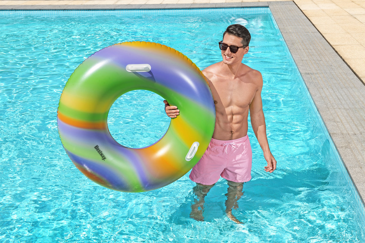 This is a lifestyle image of a man standing inside the pool and holding the inner tube on his side.