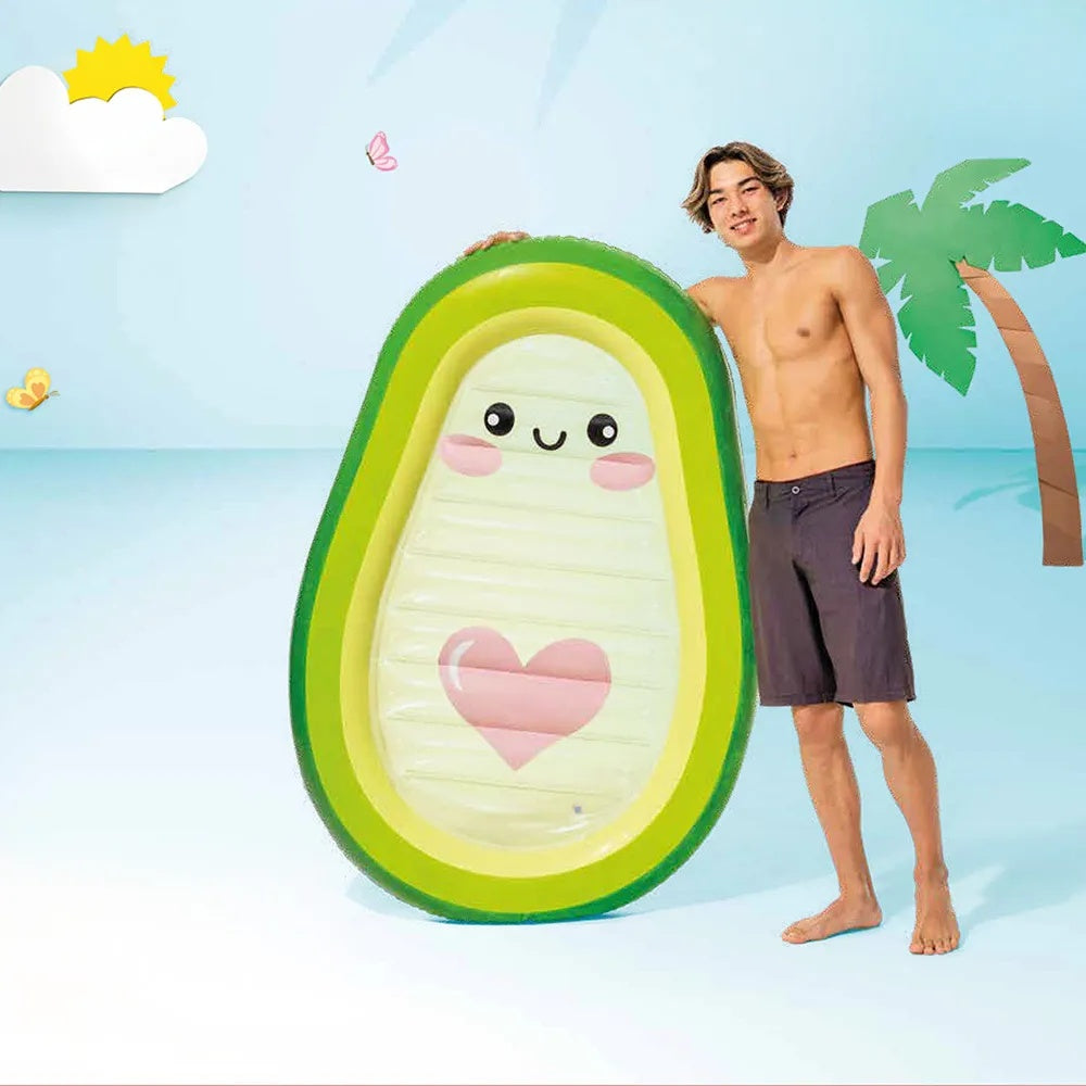 This is a lifestyle image where the backdrop looks like it's made out of colored paper that's been cut to look like a sun, cloud, palm tree, etc. There's a boy holding the avocado pool float next to his body.