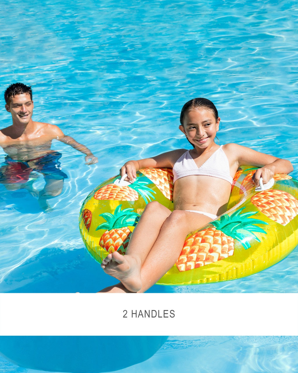 This is a lifestyle image showing a young girl resting in the pineapple inner tube. It also reads "2 handles."