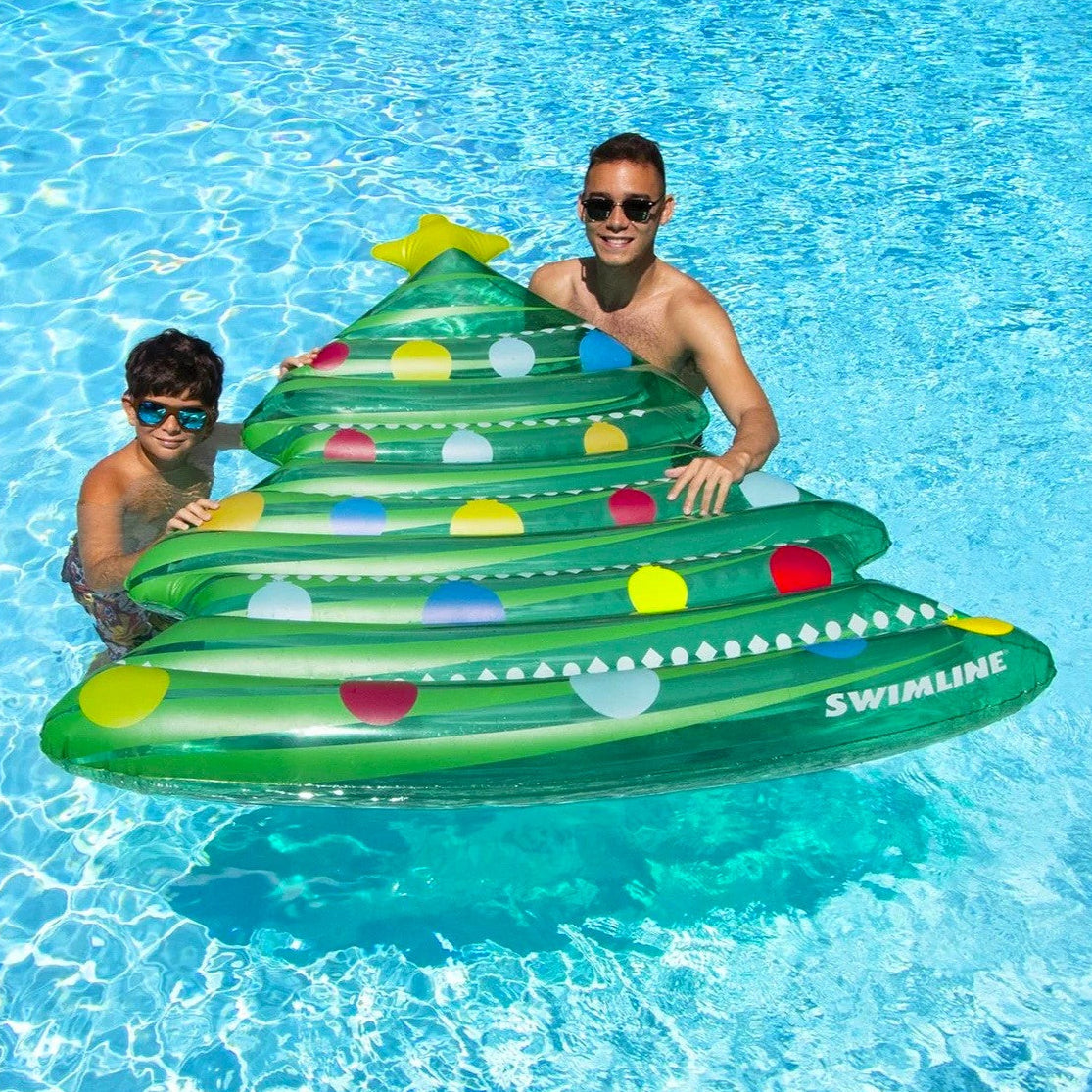 This is a lifestyle image showing a young boy and his dad holding the Christmas tree float in a pool.