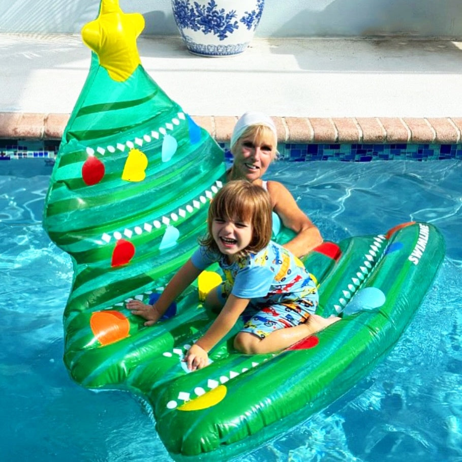 This is a lifestyle image showing a young child playing on the tree float in a pool while their Grandma looks on.