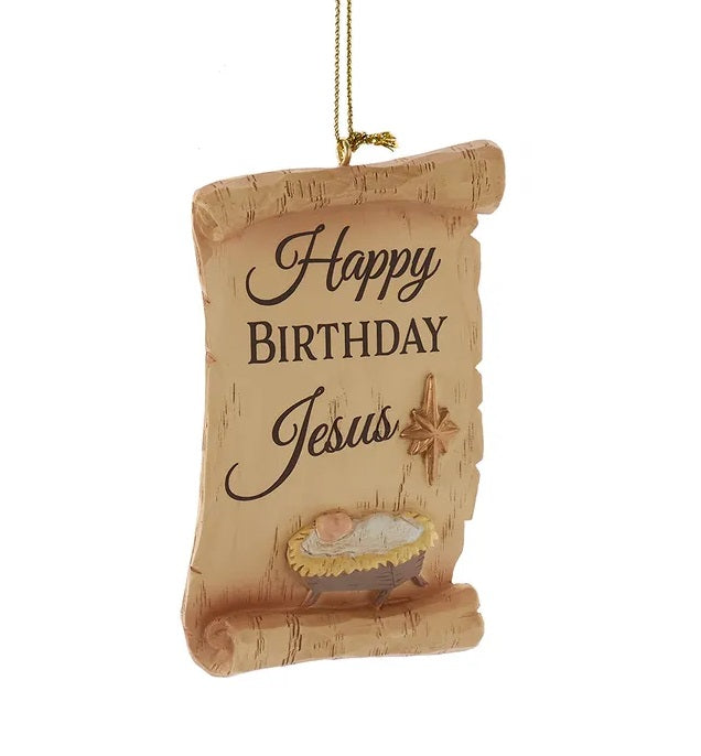 This image shows a brown scroll ornament that reads "HAPPY BIRTHDAY JESUS" and features baby Jesus in a manger.