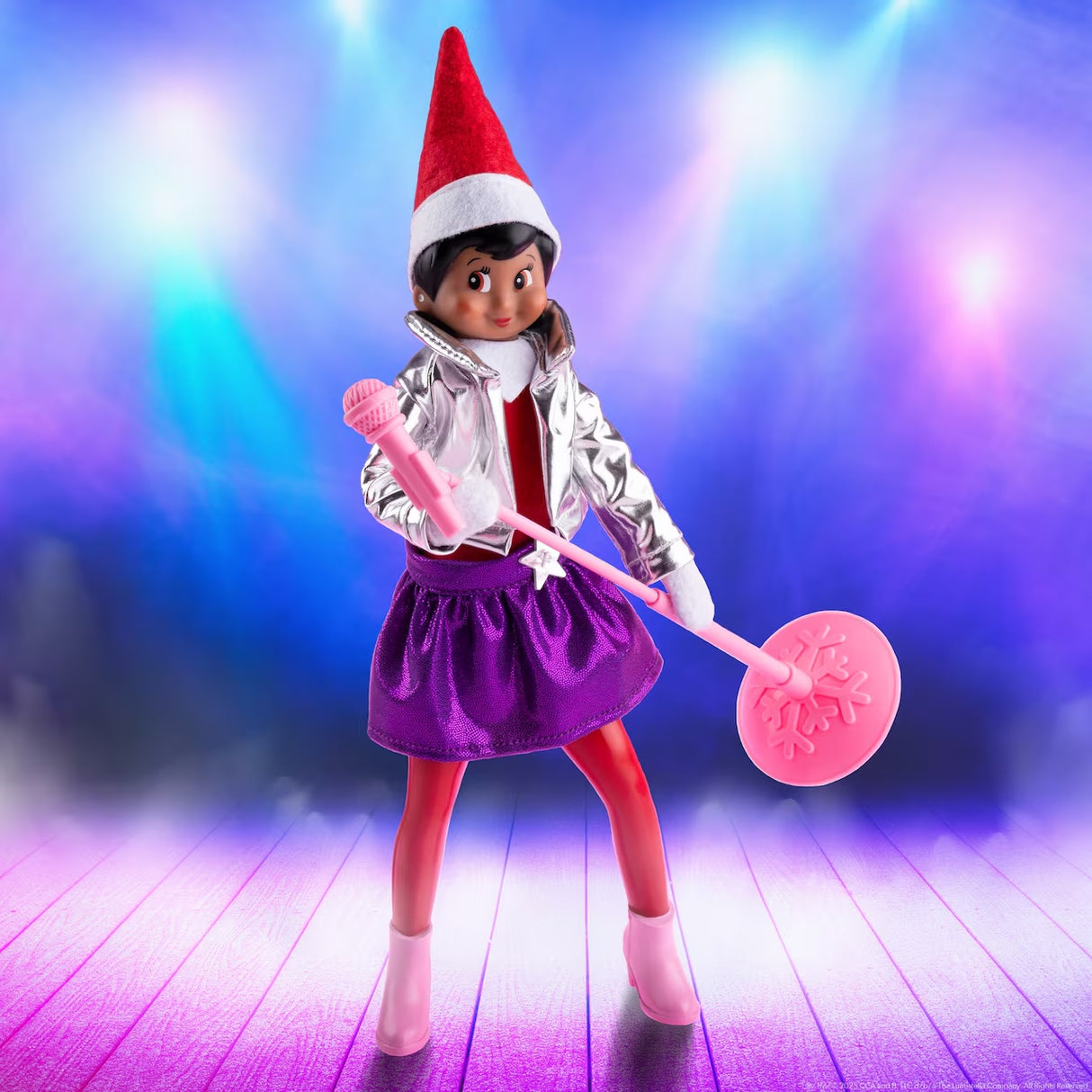 This is a lifestyle image making it look like this Scout Elf in the Pop Star outfit is on a stage with bright lights behind her.