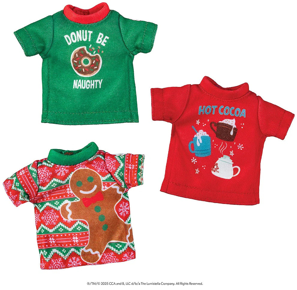 This image shows the three different festive elf shirts on a white background. One is green with a red collar and it reads "Donut Be Naughty" and features a donut with a bite taken out of it. One is red and reads "Hot Cocoa" and features three different mugs with whipped cream on them. One is red and white striped with a green collar and it features a large brown gingerbread cookie with a red bowtie.