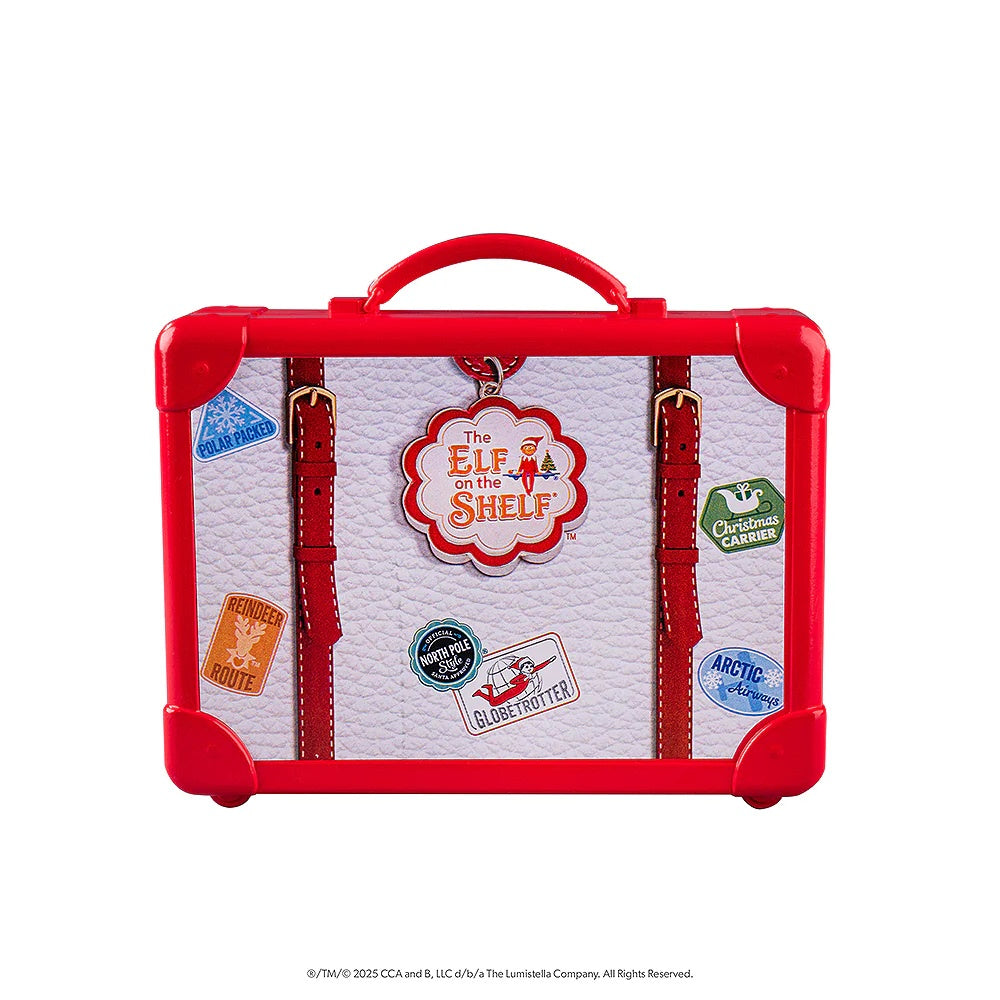 This image shows the elf-sized suitcase that comes in this kit. It's a white suitcase with red accents. There are different stickers on it. One is blue and reads "Polar Packed." One is orange and reads "Reindeer Route." One is black and teal and reads "Official North Pole Style Santa Approved." One is white and reads "Globetrotter." One is green and reads "Christmas Carrier." One is blue and reads "Arctic Airways."
