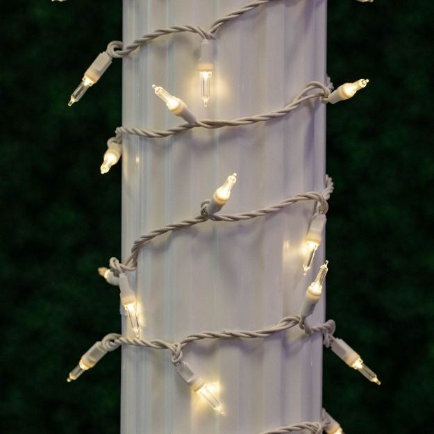 This is a lifestyle image showing these warm white lights on a white wire wrapped around a column outside.