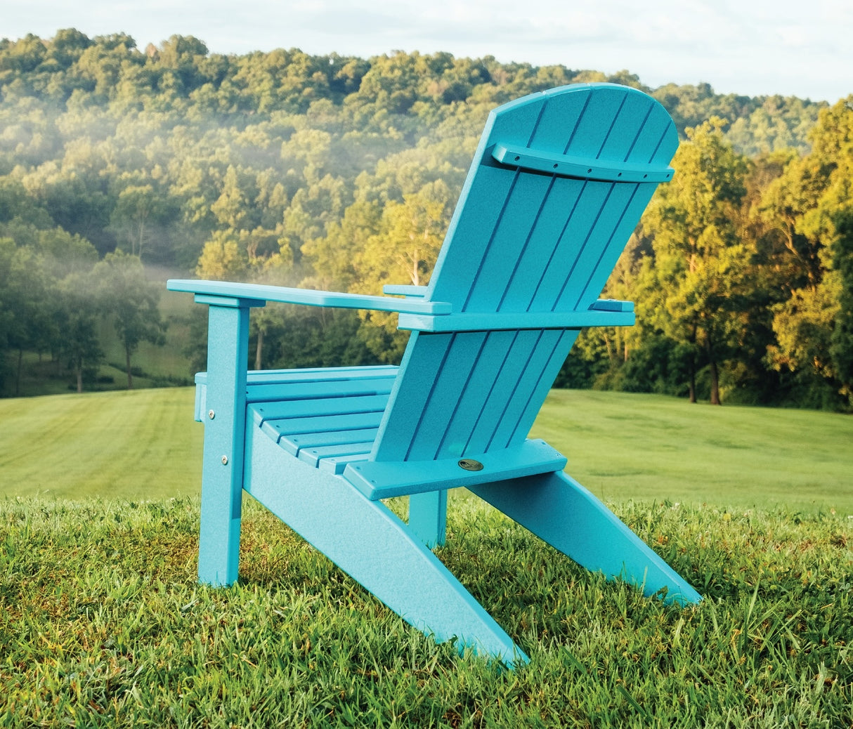 A light blue adirondack chair in a grassy field.