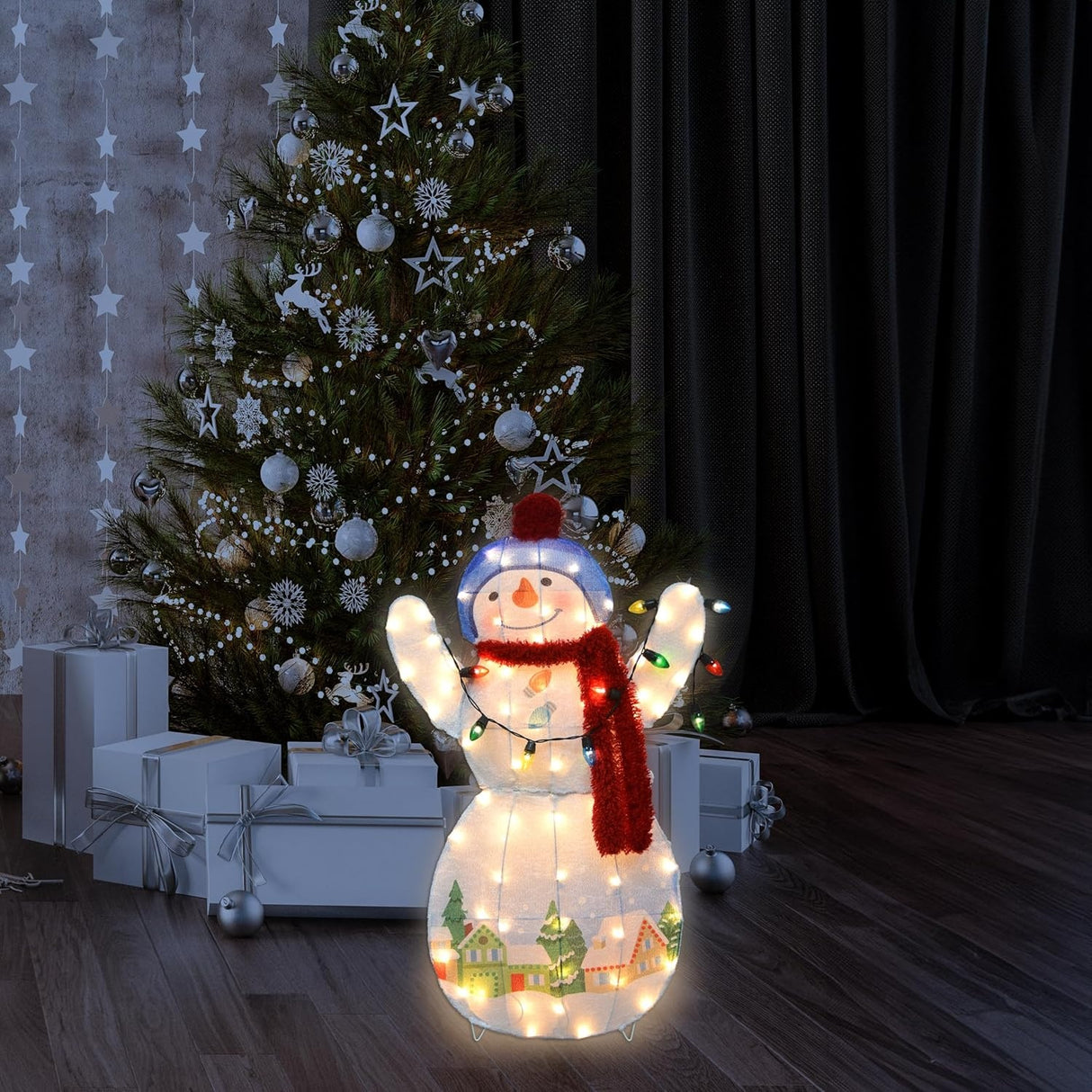 This is a lifestyle image showing the snowman sculpture lit up in front of a decorated Christmas tree in a living room.
