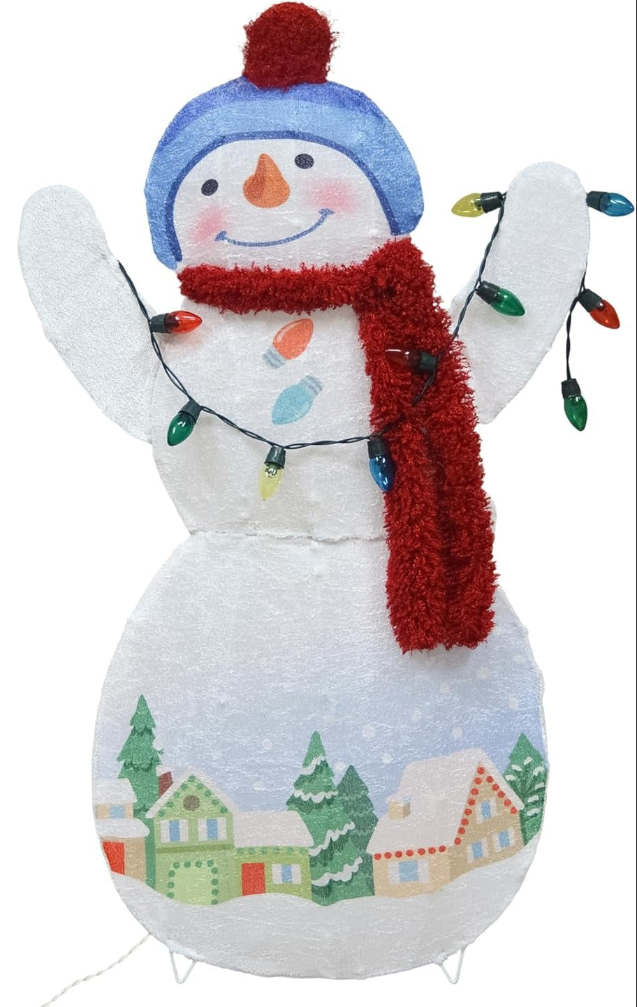 This image shows the snowman sculpture decoration on a white background. The snowman is wearing a blue winter hat with a red poof on top and a red scarf. The snowman is holding a string of multi-colored light bulbs. The snowman has two eyes, a carrot nose and a cute smile with rosy cheeks. At the bottom of the snowman, there's a winter scene consisting of different homes and trees covered in snow.