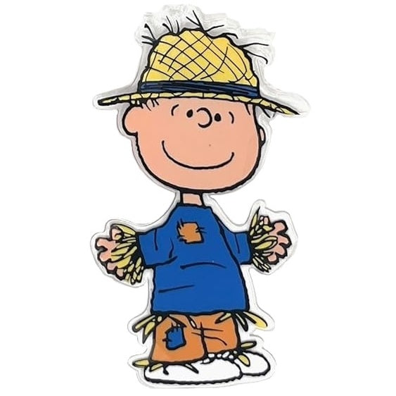 This image shows one of the gel clings. It's designed to look like Linus dressed up like a scarecrow. He's wearing a straw hat, a blue shirt with an orange patch on it, orange pants with a blue patch and white shoes. The shirt and pants are stuffed with straw.