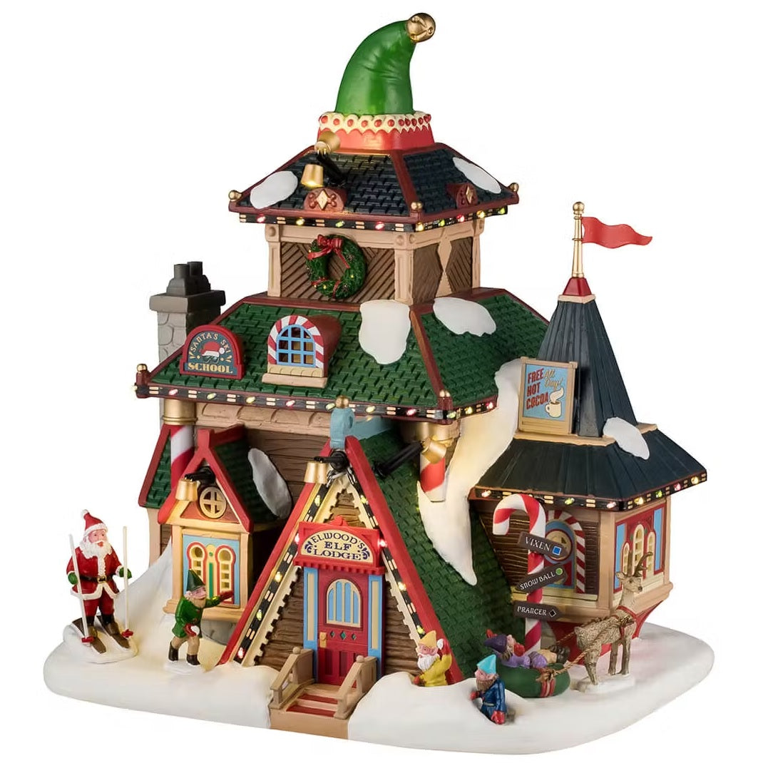 This is a Lemax building that has three stories. The top has a large, decorative elf hat. All three of the roofs are covered in snow. There's a wreath accent and candy cane accents. Santa stands out front on skis. There are elves all over and a reindeer.