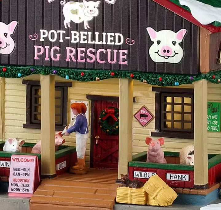 This is an up close view of this building. There's a sign near the front door that reads "WELCOME! WED-SUN 8 am-4 pm. ADOPTION: MON-TUES NOON-5 pm." There's a wreath on the door and a cat laying on the hay.