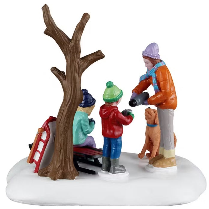 This is a different view of this table accent. You can see the mom pouring hot chocolate into her son's mug and a sled leaning up against the tree.