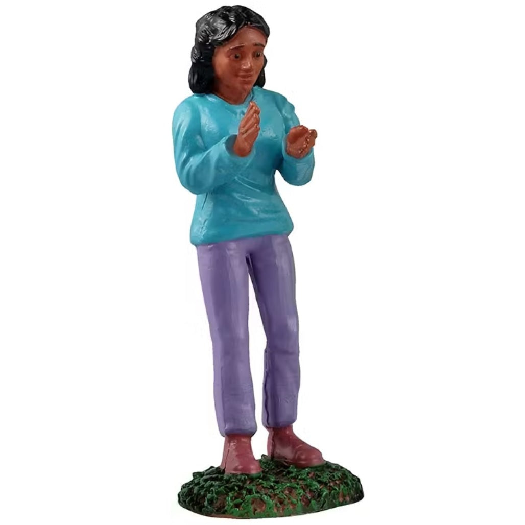 This figurine is a woman wearing a blue sweatshirt and purple pants and she's clapping her hands together.