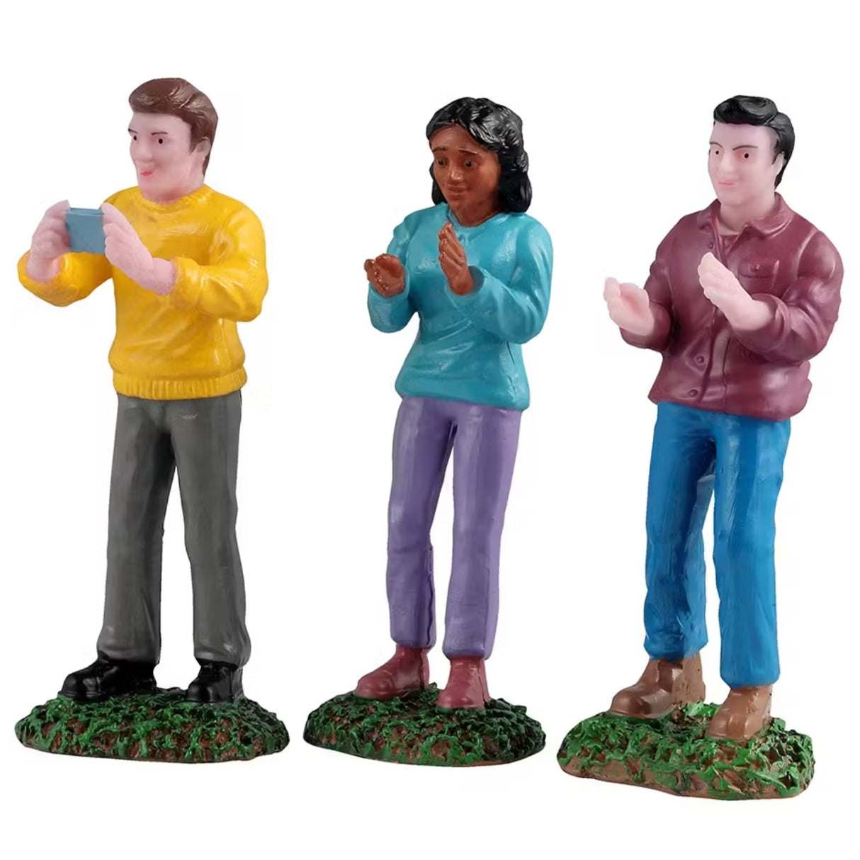 This is a set of three Lemax figurines designed to look like three people standing in grass at a concert.