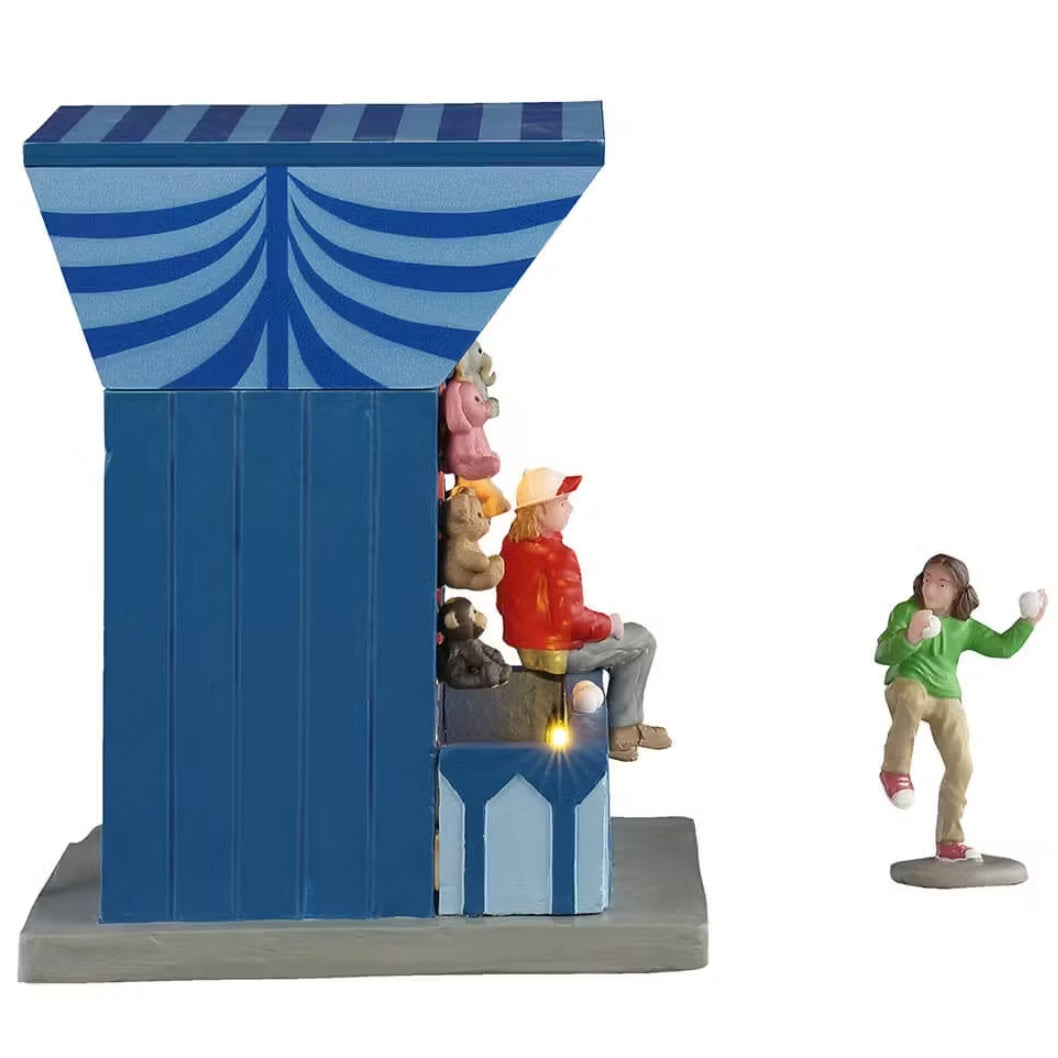 This is the side profile of this Lemax booth. You can see the girl gearing up to throw the ball and you can see the booth worker sitting on the booth table.