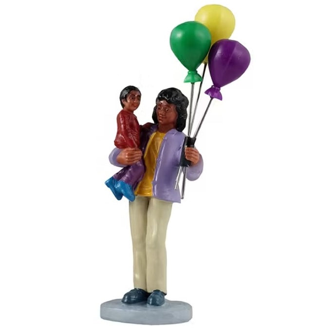 This figurine shows a mom holding a child in one hand and a set of yellow, green and purple balloons in the other.