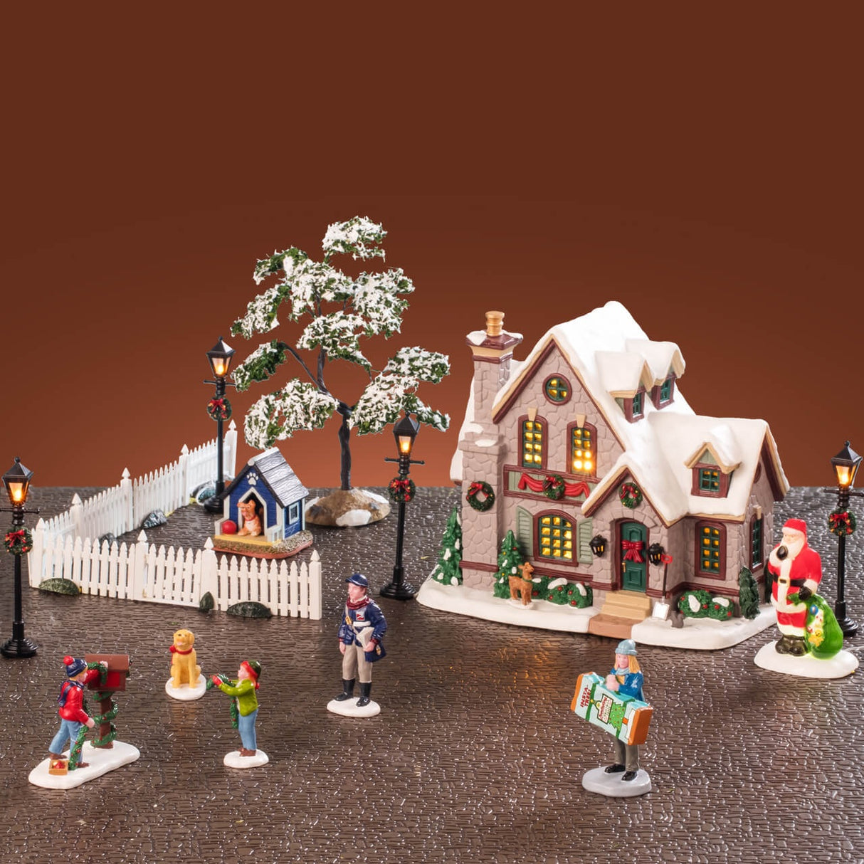 This is a lifestyle image showing the set on display. There's a house, six pieces of a white fence, a dog house, a tree, four lamp posts and five figurines.