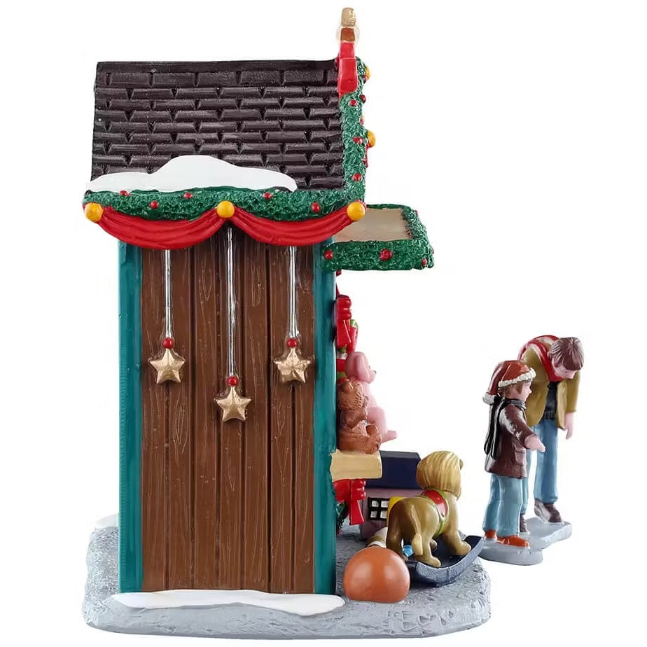 This is the side of the booth. There's snow on the roof and three gold stars dangling from the roof. You can see the boy is wearing a Santa hat and his dad is leaning down to listen to what his son is saying.