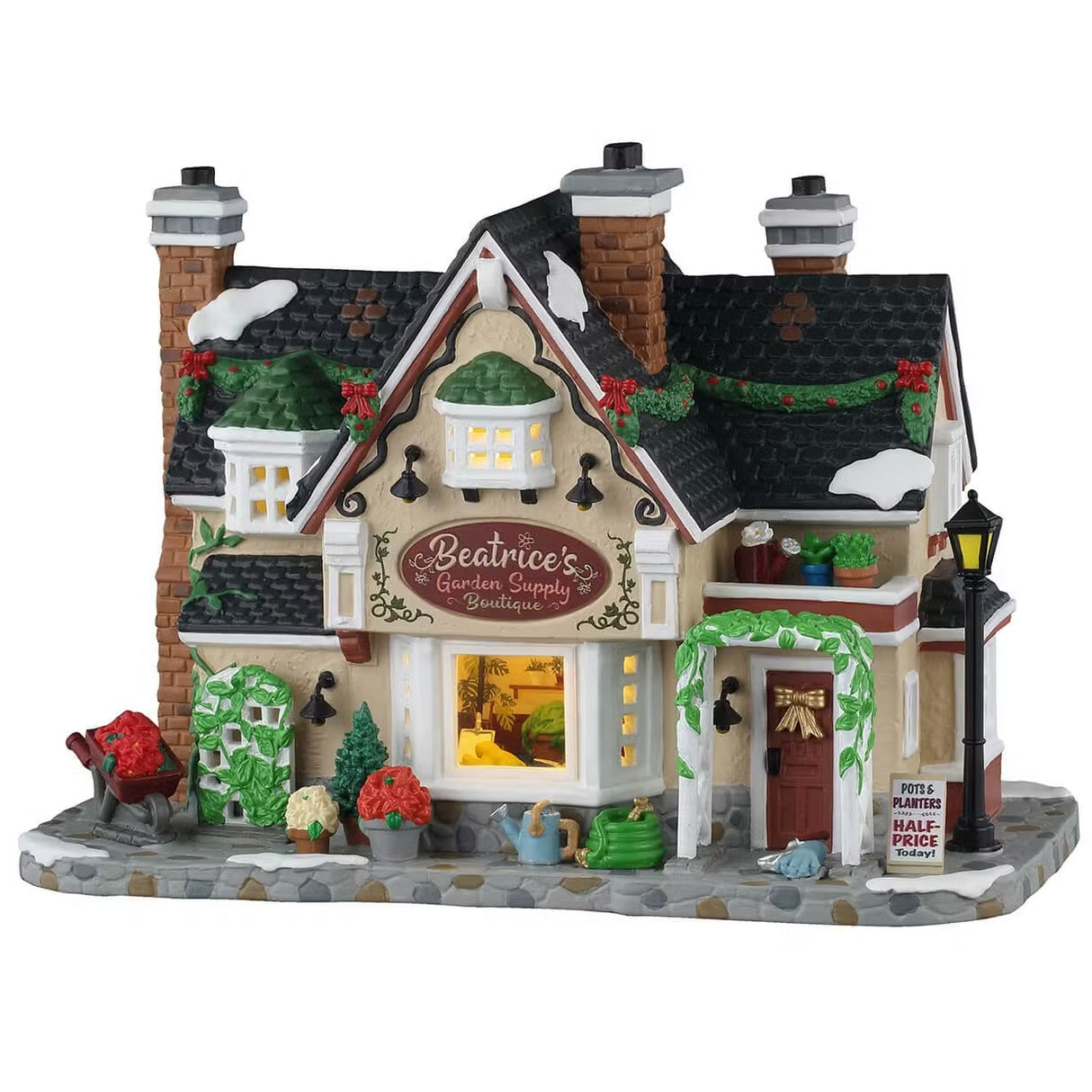 This is a Lemax lighted building designed to look like a cozy cottage turned into a plant shop. There's snow on the roof and on the sidewalk. It's decorated with garlands and red ribbons. There's an arch above the door decorated with ivy. There's a lamp post off to the left side of the front door. There's a wheelbarrow full of roses and potted plants everywhere. There's a watering can and a hose underneath the window.