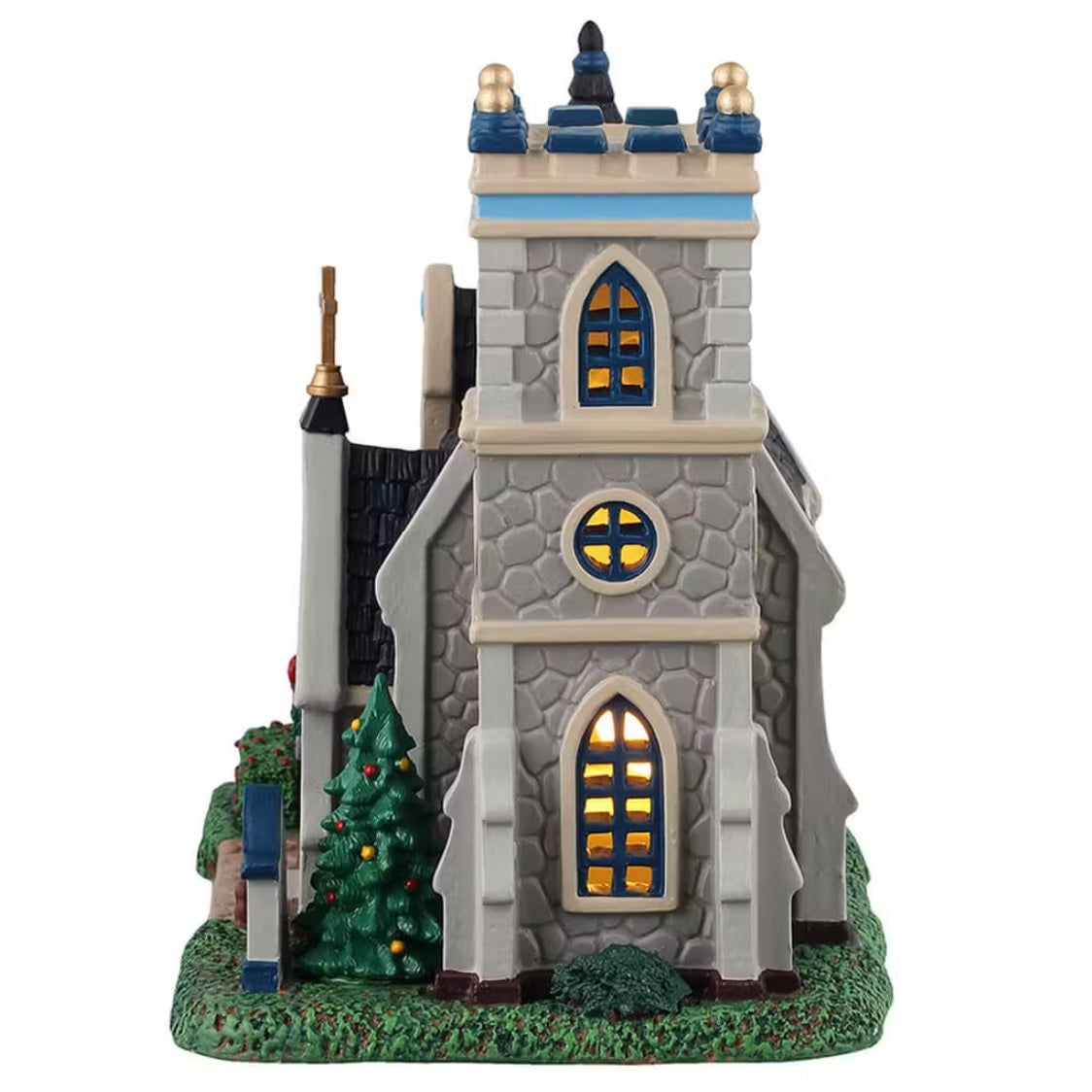 This is the other side of the building. There are three windows with lights shining through. There's a decorated Christmas tree in front.