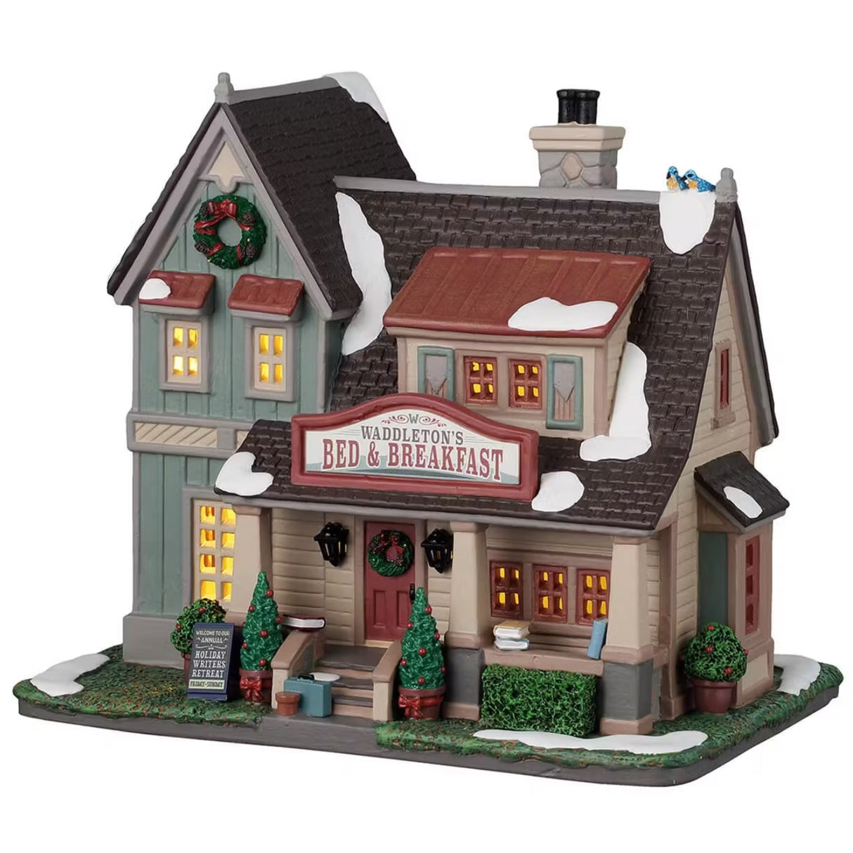 This is a Lemax lighted building. There's a sign above the front door that reads "WADDLETON'S BED & BREAKFAST." There's a wreath near the roof and a wreath on the front door. There are decorated potted trees on either side of the front stairs. There's a sign on the front lawn that reads "WELCOME TO OUR ANNUAL HOLIDAY WRITER'S RETREAT. FRIDAY THROUGH SUNDAY."