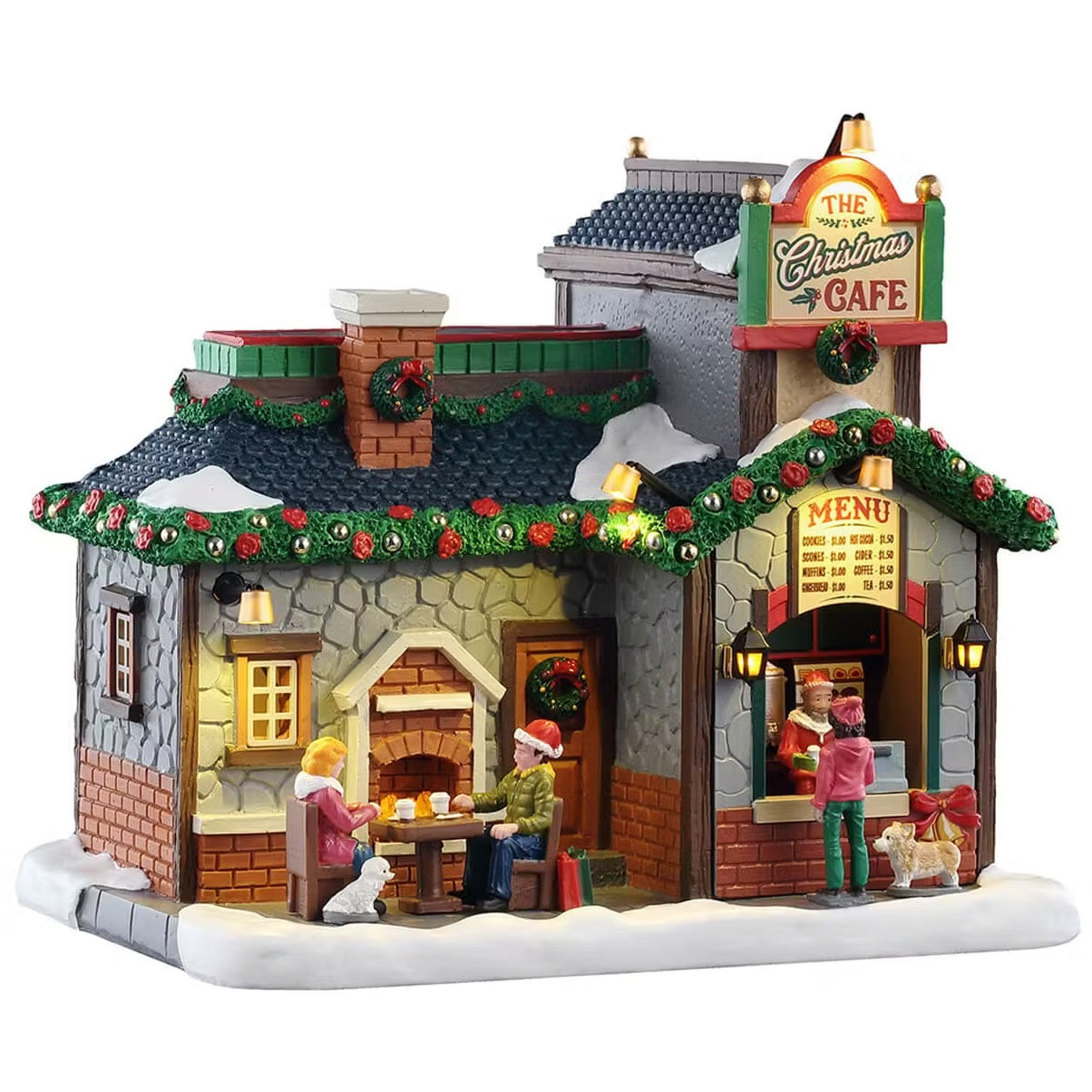 This is a Lemax lighted building designed to look like a small, stone restaurant. The roof is decorated with garland and wreaths. There's snow on the roof and on the sidewalk. There are two people eating at a table outside and they have a little white dog with them. There's someone ordering from the outdoor register and they have a small dog with them.