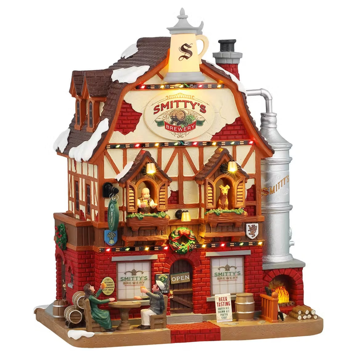 This is a Lemax lighted building designed to look like a tall, rustic, brick brewery. There are people drinking at a table in front and barrels everywhere. There's a brick fireplace on the right side. There's a man looking out the window on the left and a dog looking out the window on the right. There's snow on the roof.