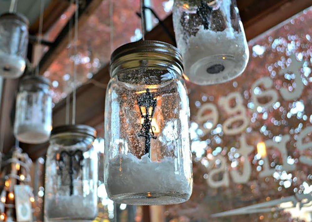 This is a lifestyle image showing some mason jars hanging as decorations. Inside the mason jars, there's faux snow and miniature lampposts.