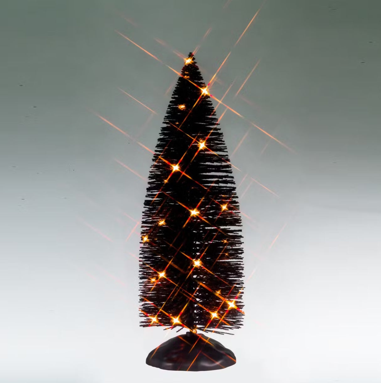 This is a Lemax Spooky Town tree with black bristle branches pre-lit with orange lights. This is showing the tree on a gray background.