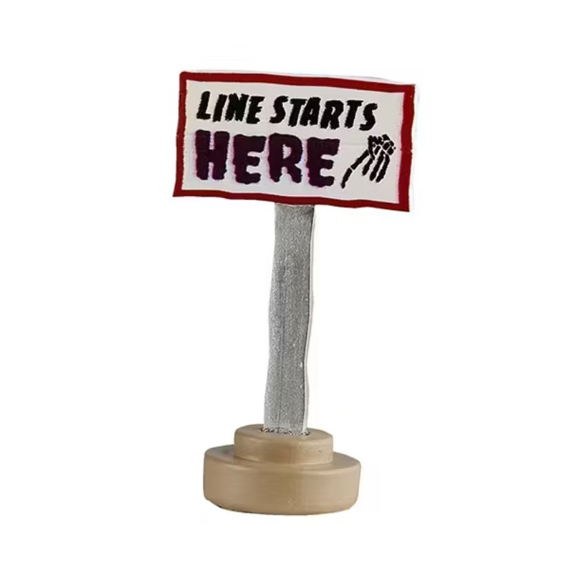 This is a pole with a sign on it that reads "LINE STARTS HERE" and has a skeleton hand pointing down.
