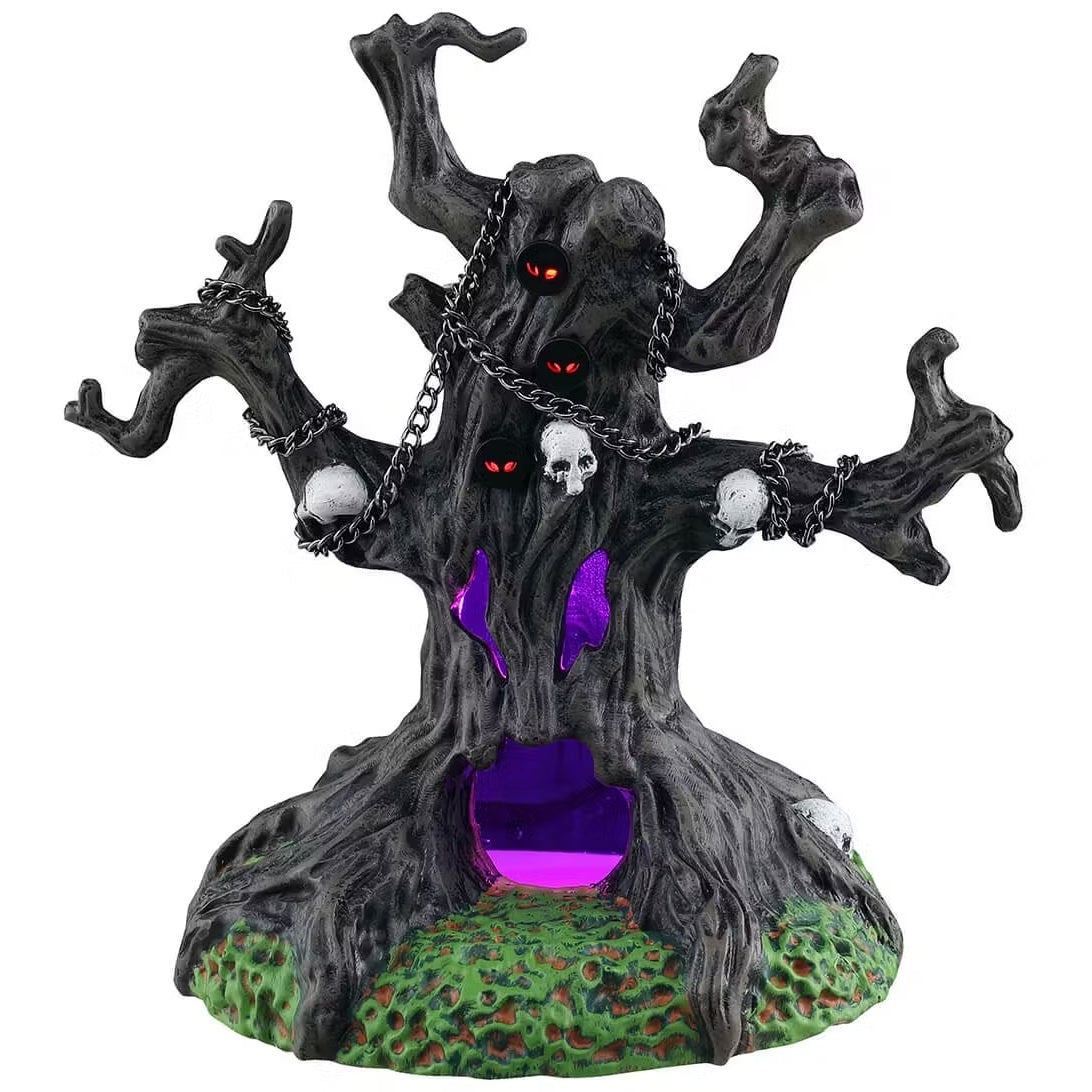 This is a Lemax Spooky Town table accent designed to look like a creepy tree with no leaves on the branches. There are chains and skulls wrapped around a few branches. There are a few holes with red glowing eyes. There's also two eyes and a large mouth that glows purple inside.