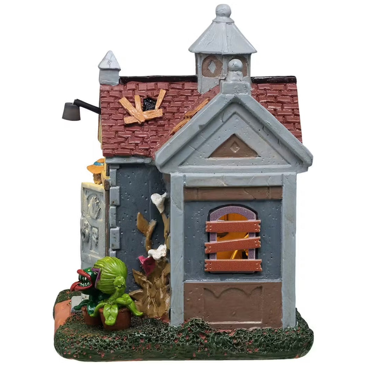 This is a different angle of this Lemax Spooky Town building that's designed to look like a rundown garden shed. There are holes patched up with slats of wood, windows boarded up and plants with teeth growing near the front door. A woman wearing a blue dress and a white apron is standing near the front door holding a basket.