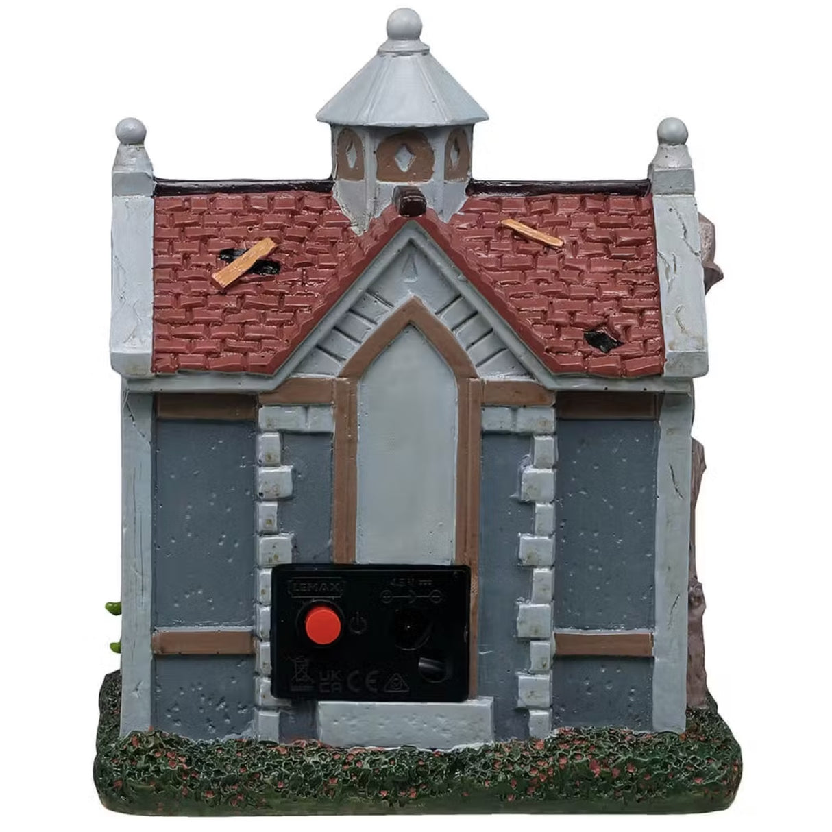 This is a different angle of this Lemax Spooky Town building that's designed to look like a rundown garden shed. There are holes patched up with slats of wood, windows boarded up and plants with teeth growing near the front door. A woman wearing a blue dress and a white apron is standing near the front door holding a basket.