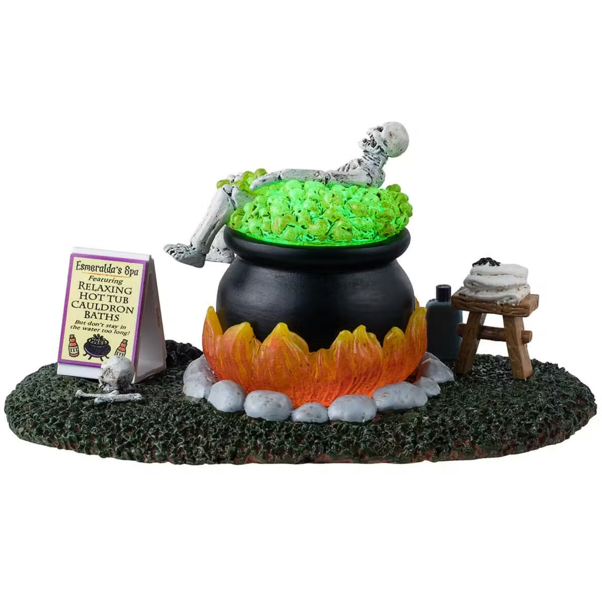 A different angle - This is a Lemax Spooky Town table accent designed to look like a skeleton taking a bath in a big, black cauldron. The water glows green. There's a stool with a towel and a spider on it. Next to the cauldron, there's a tube of Spa Bath Soap. There's a sign next to the cauldron that reads "Esmeralda's Spa featuring Relaxing Hot Tub Cauldron Baths. But don't stay in the water too long!"
