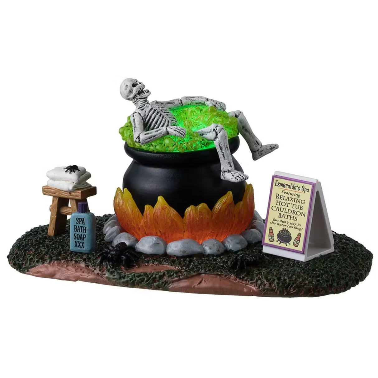 This is a Lemax Spooky Town table accent designed to look like a skeleton taking a bath in a big, black cauldron. The water glows green. There's a stool with a towel and a spider on it. Next to the cauldron, there's a tube of Spa Bath Soap. There's a sign next to the cauldron that reads "Esmeralda's Spa featuring Relaxing Hot Tub Cauldron Baths. But don't stay in the water too long!"