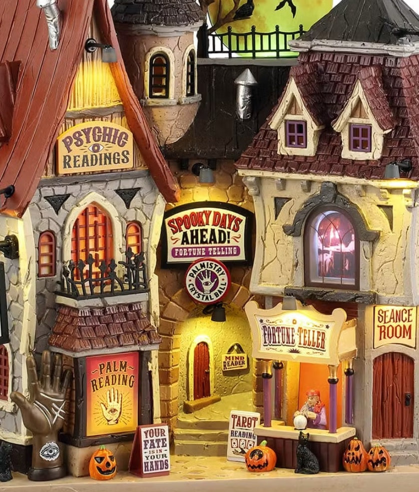 This is an up close view of the mansion. There are various signs that read "Psychic Readings," "Palm Reading," "Your Fate is in Your Hands," "Spooky Days Ahead! Fortune Telling. Palmistry & Crystal Balls," "Mind Reader," "Tarot Reading," "Fortune Teller" and "Séance Room."