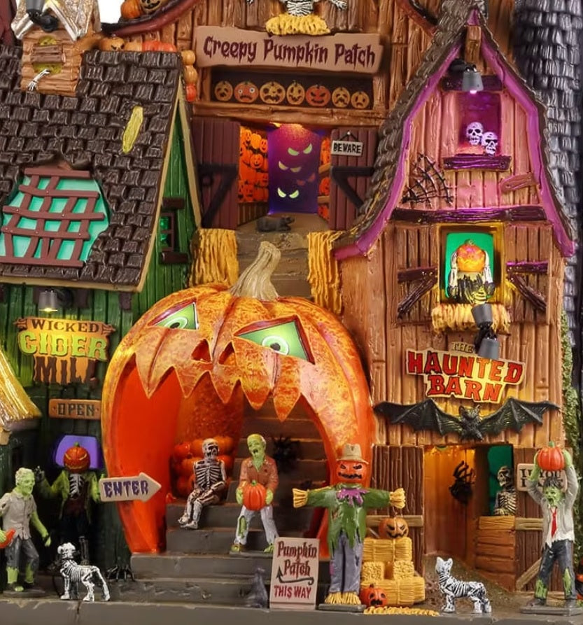 This is an up close view of this Lemax Spooky Town building facade that's designed to look like a dilapidated barn that has three different levels. One level is the Wicked Cider Mill. One level is the Creepy Pumpkin Patch. The other level is the Haunted Barn. Some accents include: weathervanes, jack-o-lanterns, skeleton cats and dogs, skulls, bats, scarecrows and bales of hay. There are several monsters and skeletons throughout.