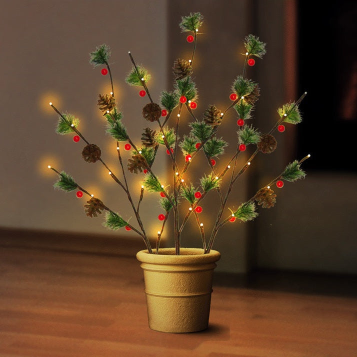 This is a lifestyle image showing the three branches staked into a flower pot on the floor inside a home. The warm white lights are on accenting the green pine needles, brown pine cones and red berries.