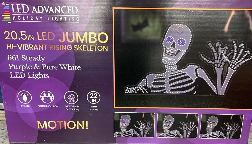 This image shows the box that the skeleton decoration comes in. It reads "20.5 in. LED Jumbo Hi-Vibrant Rising Skeleton. 661 Steady Purple & Pure White LED Lights. Continuous-On lights. Indoor/Outdoor use. 22 in. with stake."