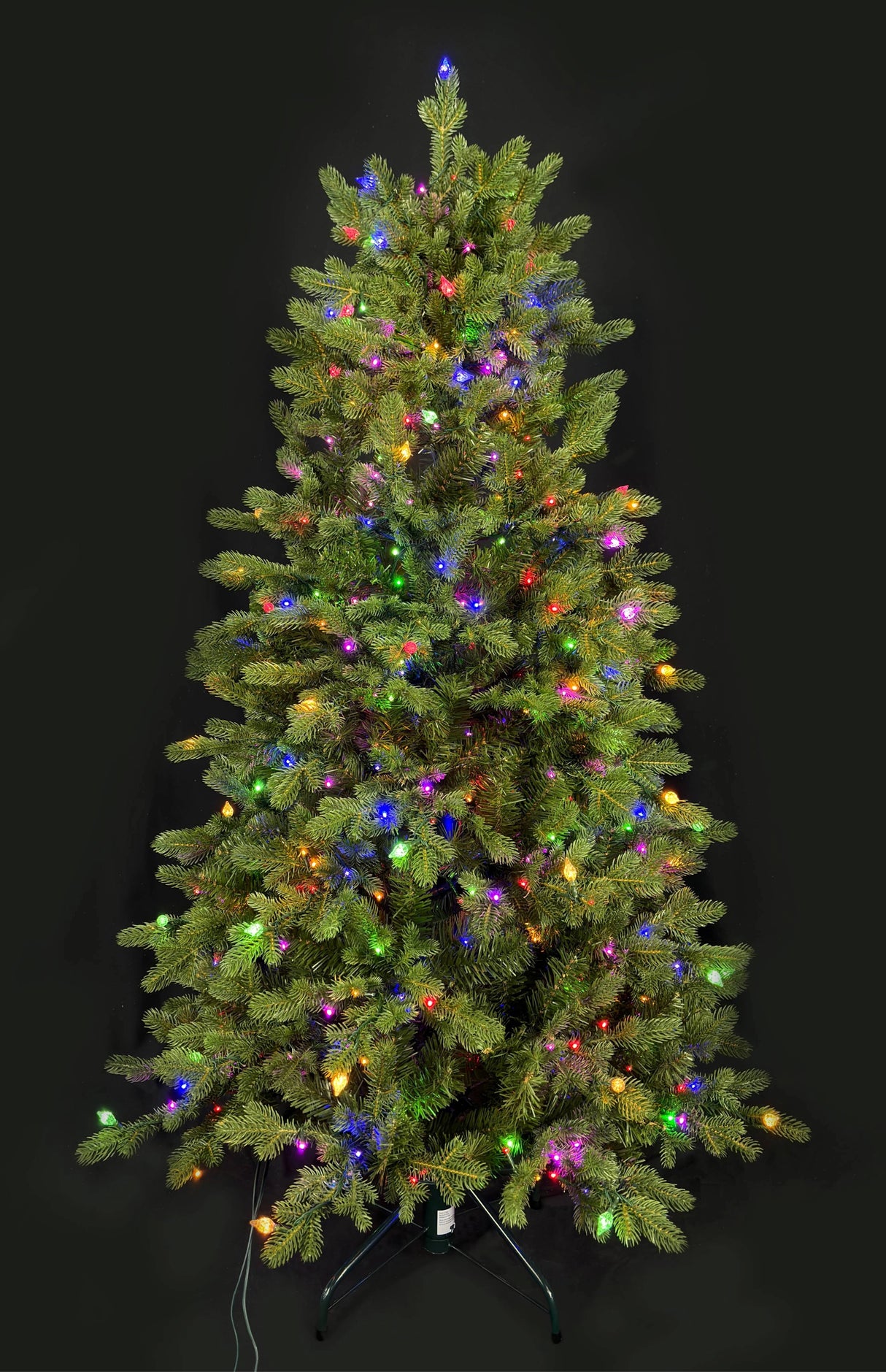 This image shows this specific artificial tree pre-lit with Multi-Colored Starry Lights. This tree is up against a black background.