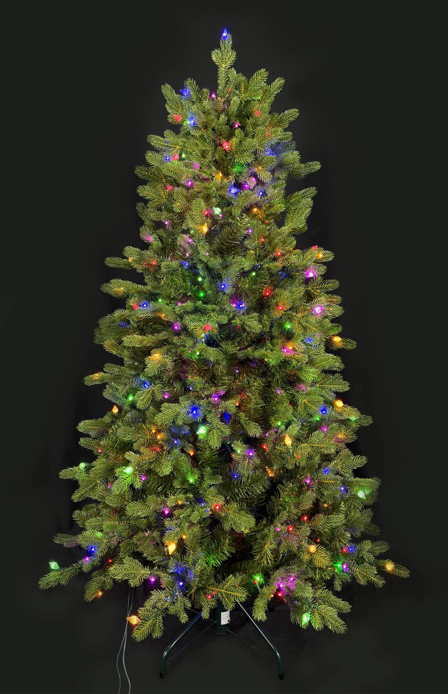 This image shows this specific artificial tree pre-lit with Multi-Colored Starry Lights. This tree is up against a black background.