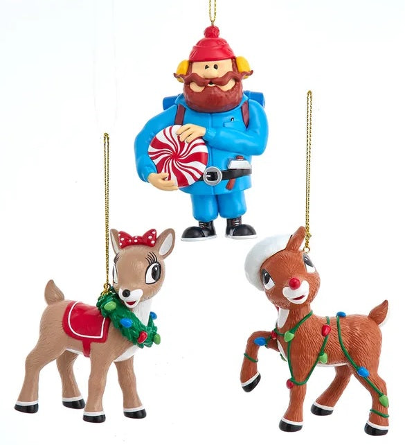 Ornaments designed to look like characters from the animated Christmas classic movie, Rudolph the Red Nosed Reindeer. One ornament is designed to look like Yukon Cornelius holding a peppermint. One ornament is designed to look like Clarice the Reindeer wearing a wreath. One ornament is designed to look like Rudolph the Reindeer wearing multi-colored Christmas lights and a Santa hat.