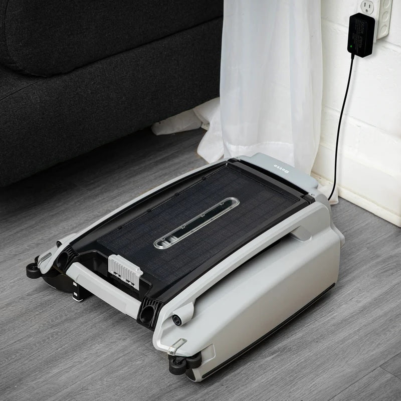 This image shows the pool cleaner plugged into an outlet next to a couch inside a home.