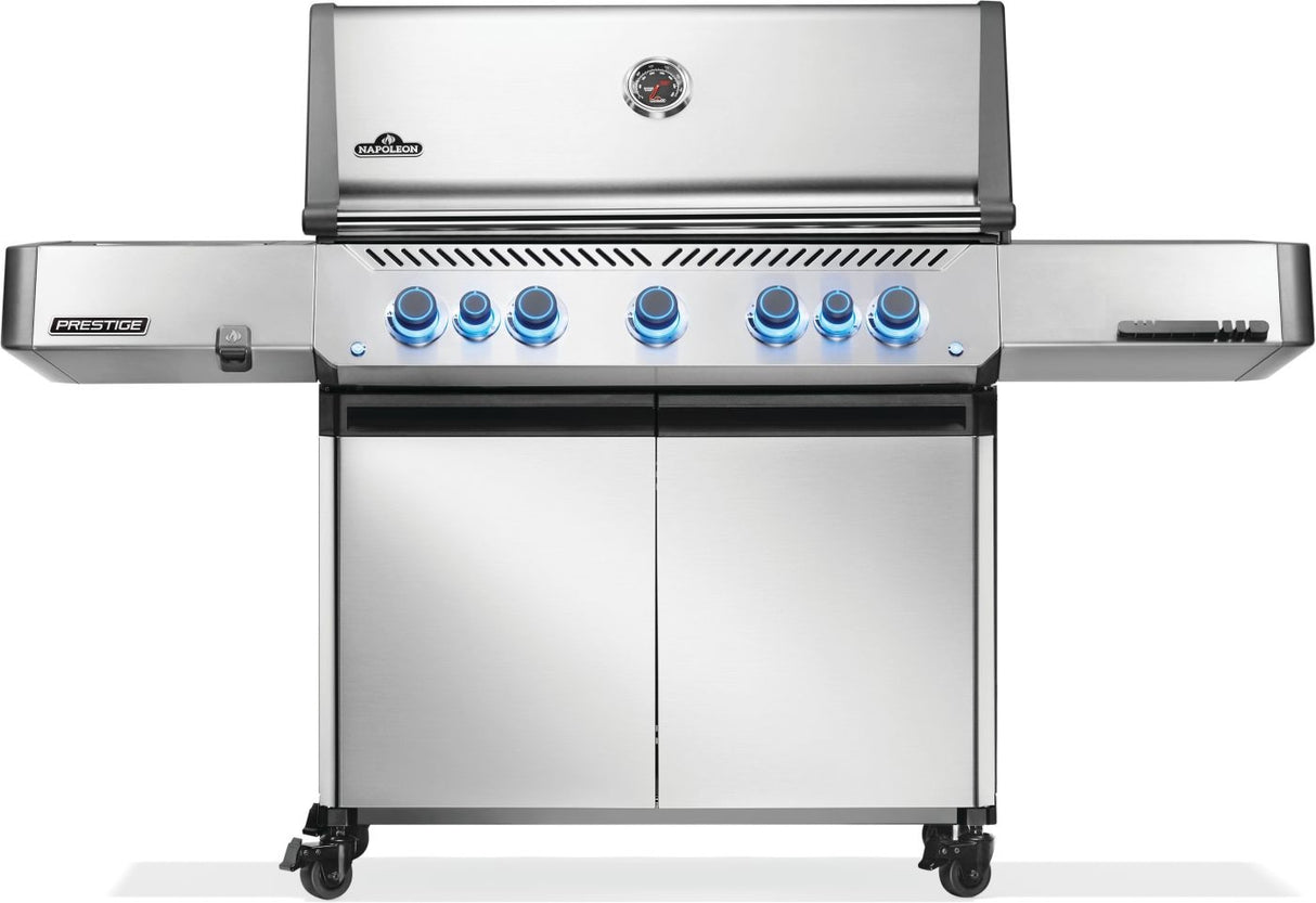 Silver and gray Napoleon grill. There is a built-in thermometer on the lid, there are two shelves outstretched, seven buttons and a cabinet that opens up underneath. This is the front view.