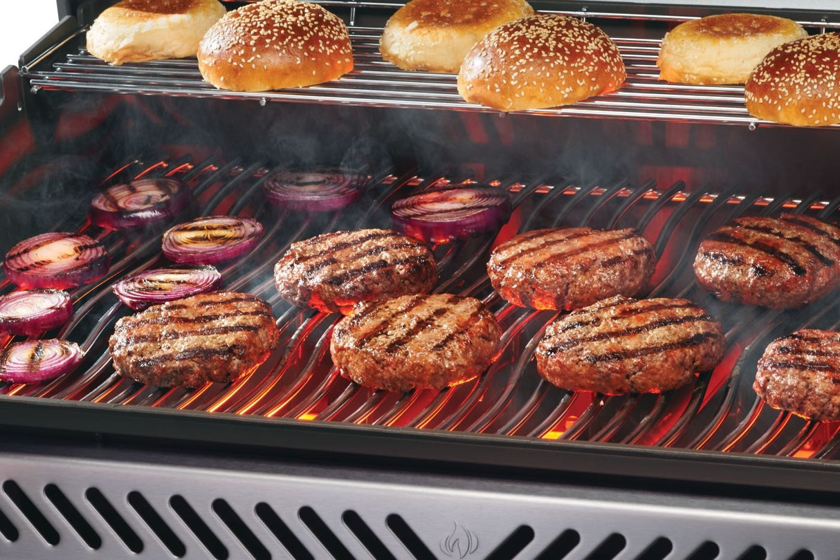 This is an up close view of the grill in use. There are buns cooking on the top shelf and onions and burgers cooking on the bottom shelf.