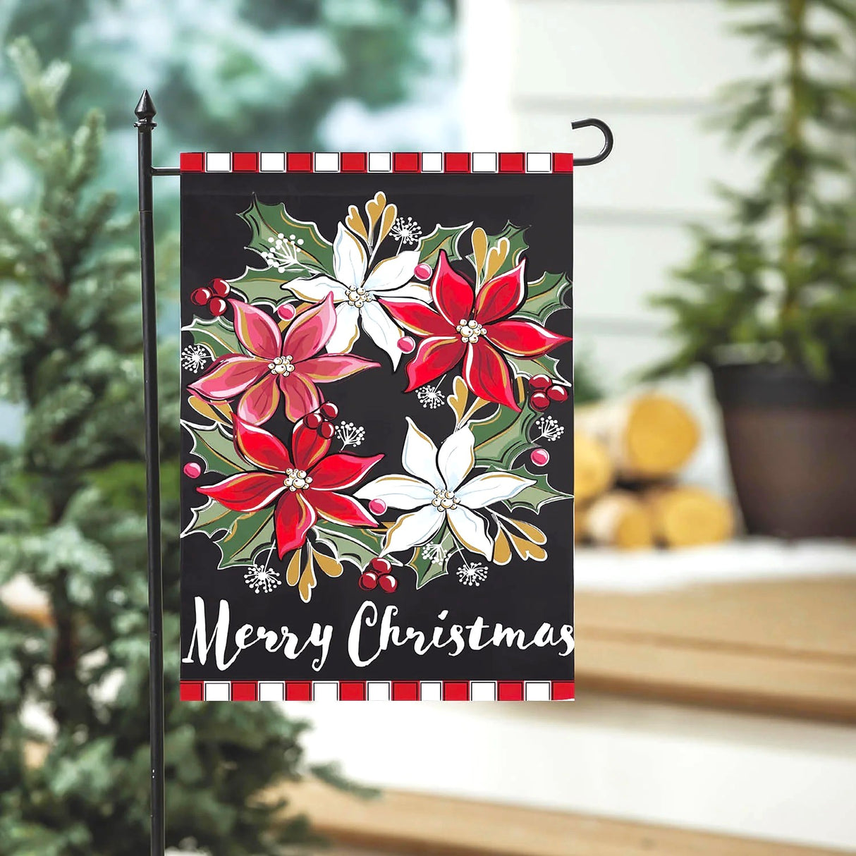 A black flag that reads "Merry Christmas" in a white, cursive font. It features a wreath made out of red, white and pink poinsettia flowers. The top and bottom border features a red and white stripe.