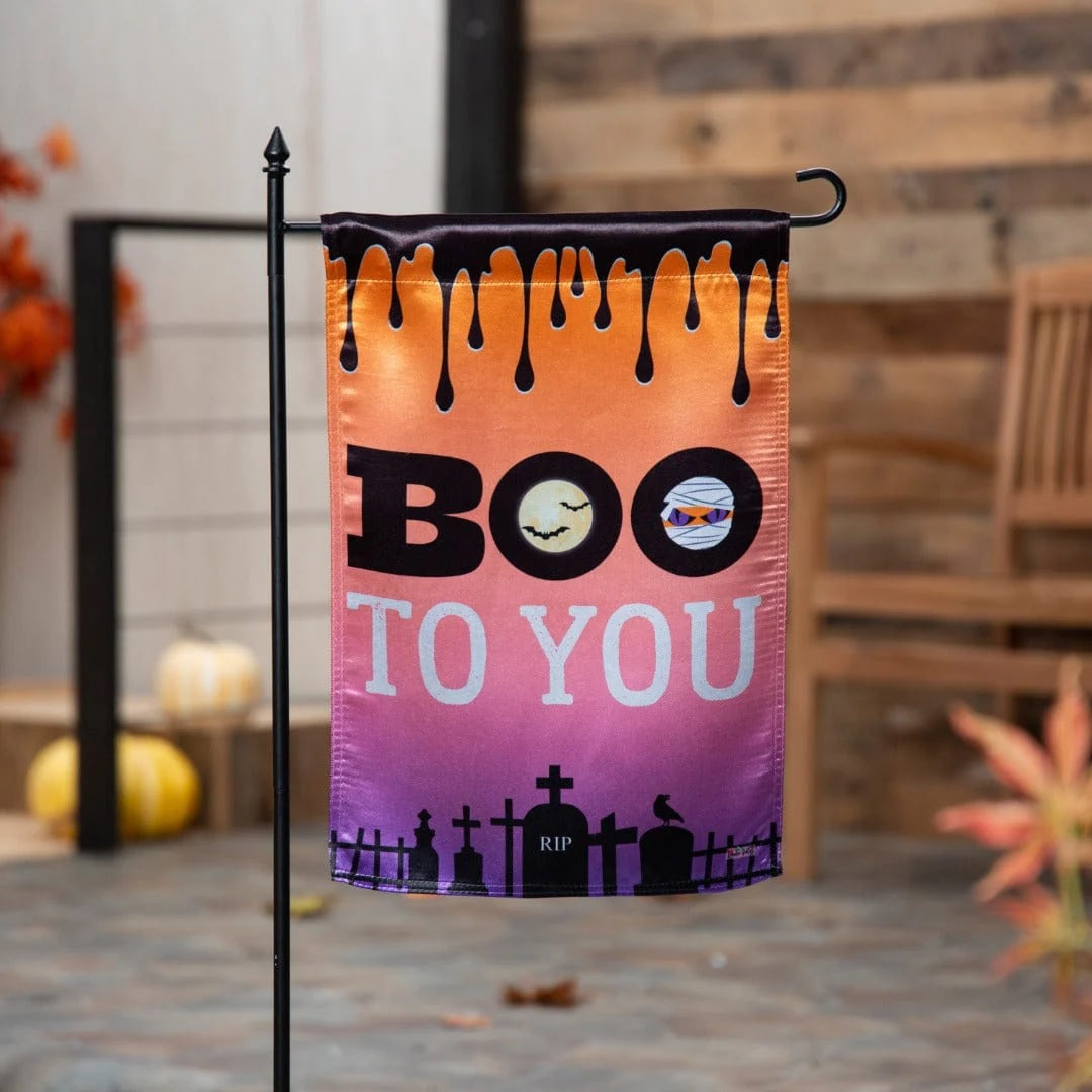 Halloween flag that reads "BOO TO YOU." The background goes from orange to pink to purple. At the top, it's designed to look like a black liquid is dripping from it. At the bottom, there's a black cemetery silhouette.